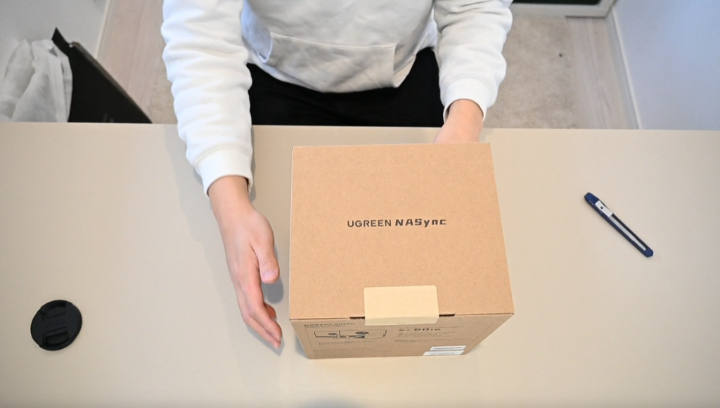 [画像：パッケージ外箱。デスクの上に置いた状態。シンプルで洗練されたデザインの箱]